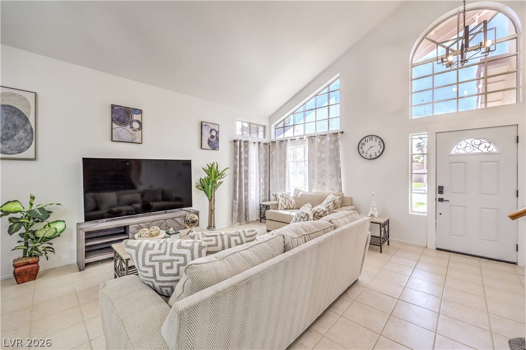 High vaulted ceilings and arched windows elevate this tiled entry and formal living space.