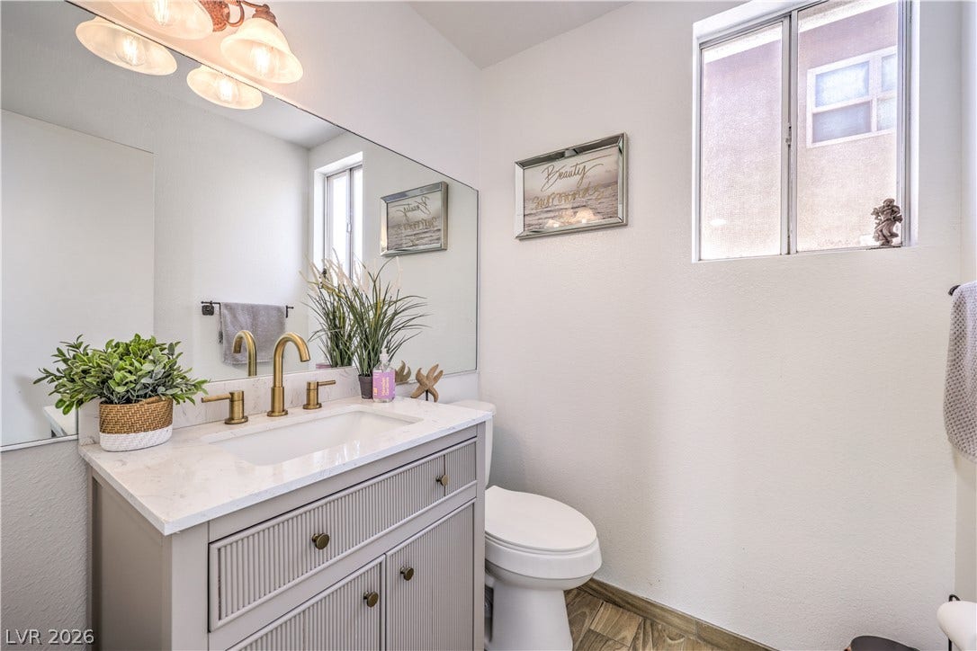 An elegant vanity with stone counters and gold fixtures anchors this modern bathroom design.