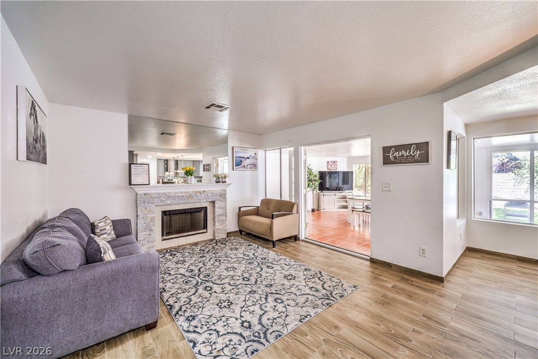 An inviting fireplace serves as the centerpiece of this versatile, light-filled living space.