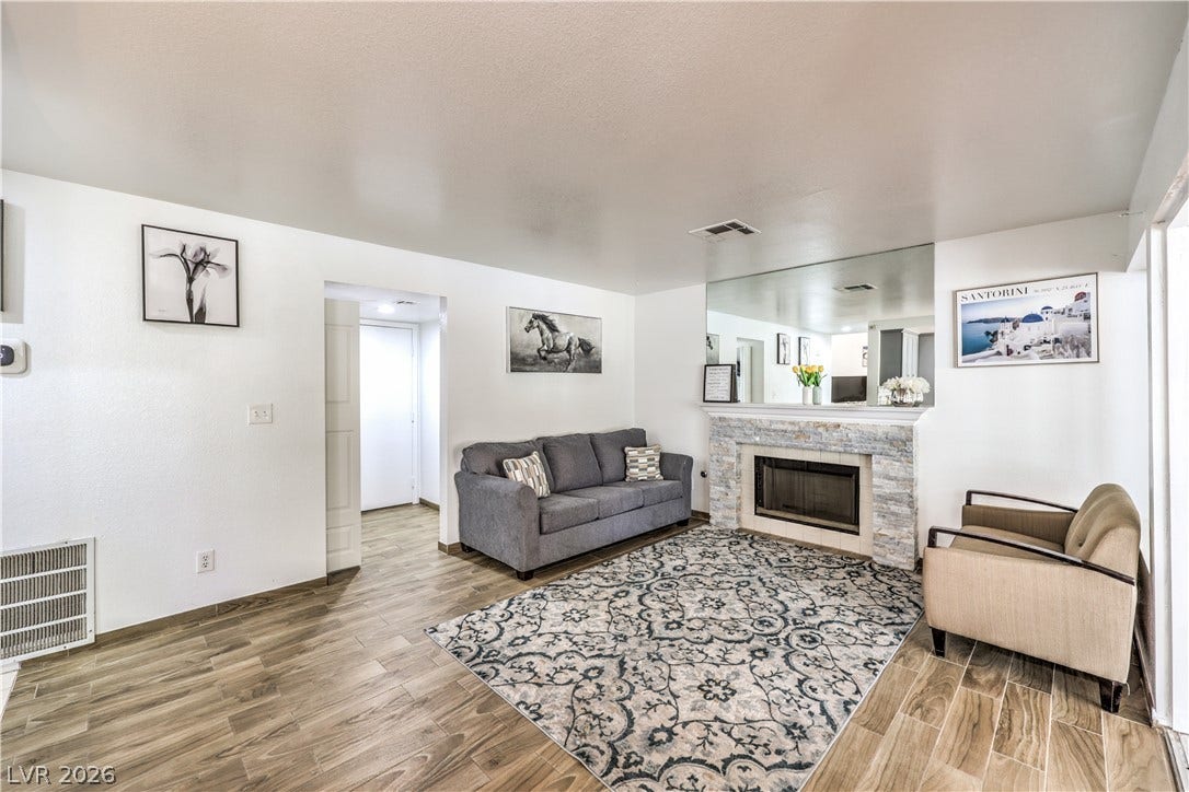 Wood-look flooring and a stone-clad fireplace anchor this inviting living space.