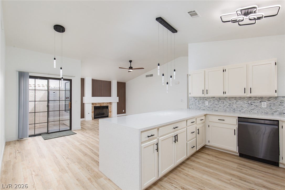 352 Lander Drive, Henderson, NV 89074 An open kitchen with stone counters and wood flooring connects seamlessly to the living area.