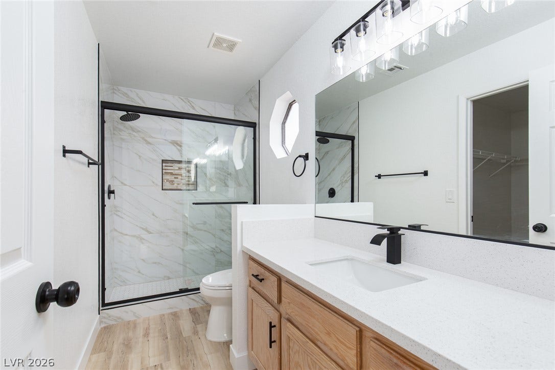352 Lander Drive, Henderson, NV 89074 Modern stone counters and a sleek glass-enclosed shower elevate this refreshed bathroom.