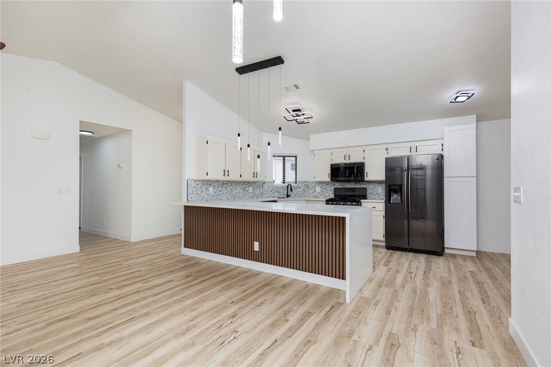 352 Lander Drive, Henderson, NV 89074 An open kitchen showcases wood-look flooring, stone counters, and a modern slatted island breakfast bar.