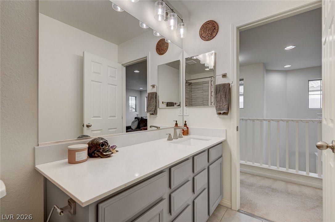 4114 Billowing Breeze Avenue, North Las Vegas, NV 89081 Smooth stone countertops and recessed lighting elevate this modern bathroom design.