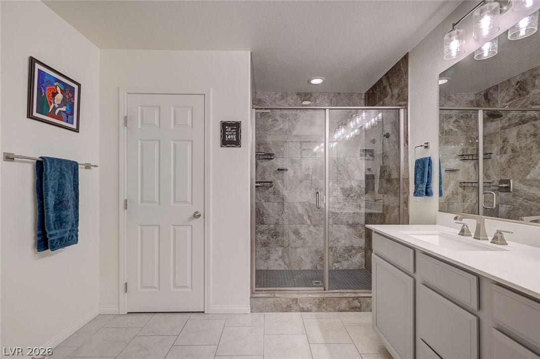 4114 Billowing Breeze Avenue, North Las Vegas, NV 89081 Polished tile flooring and a spacious walk-in shower elevate this modern bathroom design.