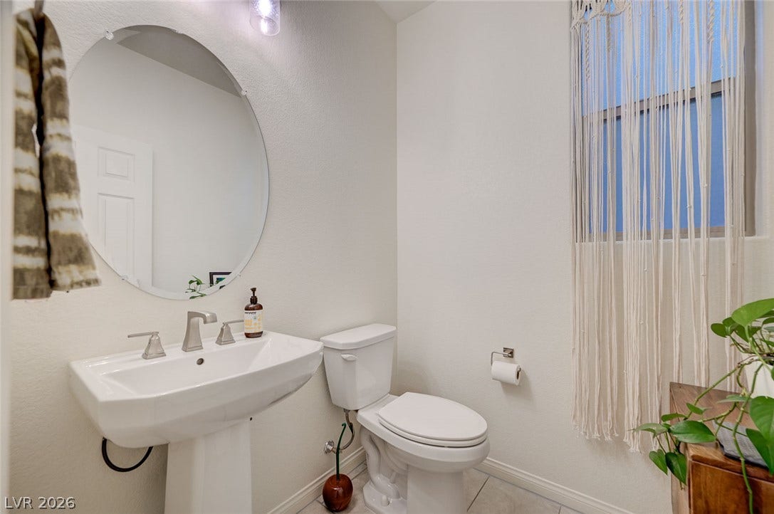 4114 Billowing Breeze Avenue, North Las Vegas, NV 89081 A classic pedestal sink paired with a round mirror anchors this neutral-toned powder room.