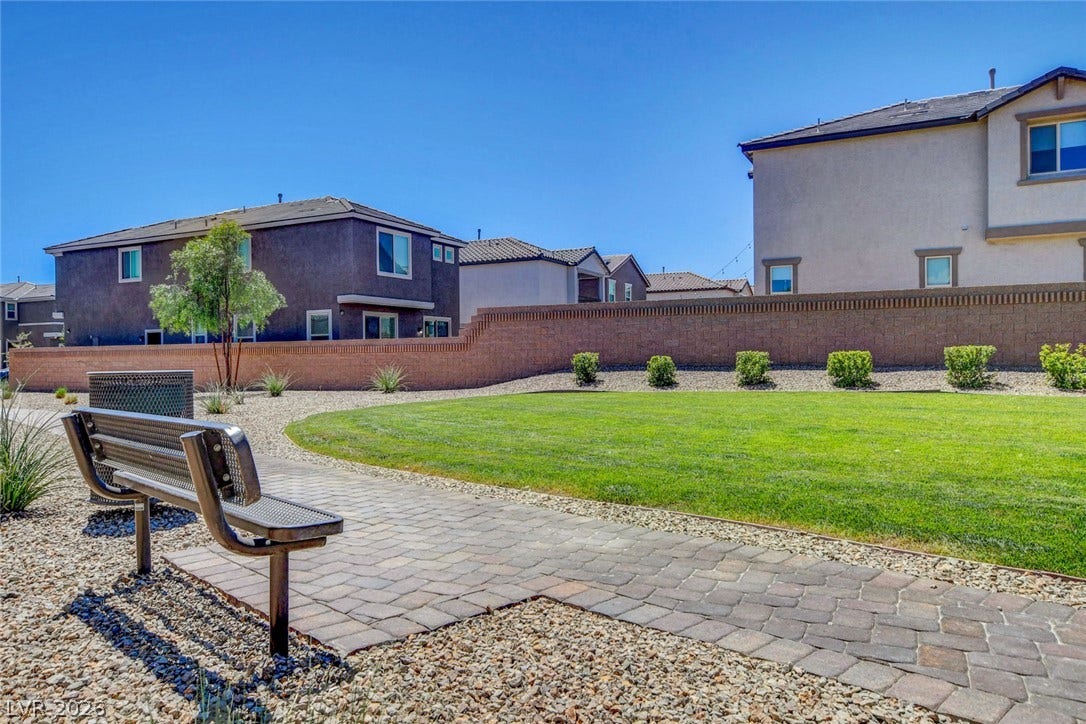 4114 Billowing Breeze Avenue, North Las Vegas, NV 89081 Manicured green space with brick-paved pathways offers a peaceful neighborhood retreat under open blue skies.