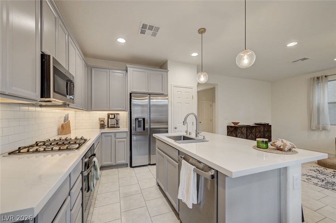 4114 Billowing Breeze Avenue, North Las Vegas, NV 89081 An open kitchen layout features sleek cabinetry, stone countertops, and modern appliances.