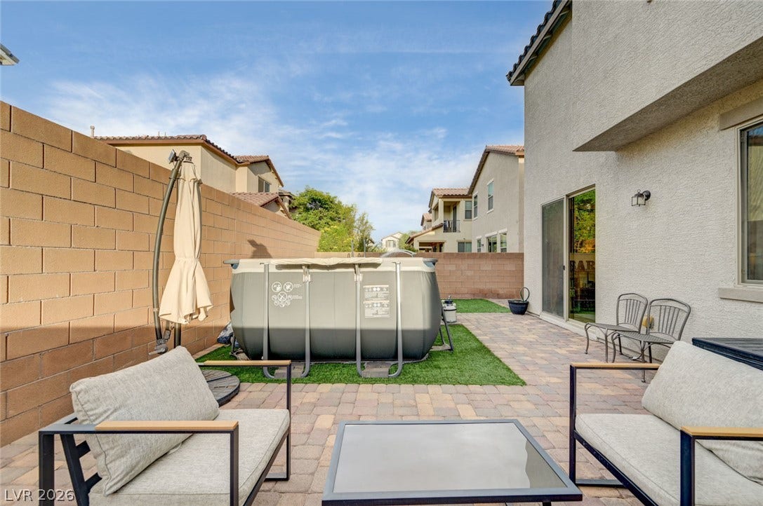 4114 Billowing Breeze Avenue, North Las Vegas, NV 89081 An inviting backyard features durable paved surfaces alongside low-maintenance synthetic turf and high block fencing.