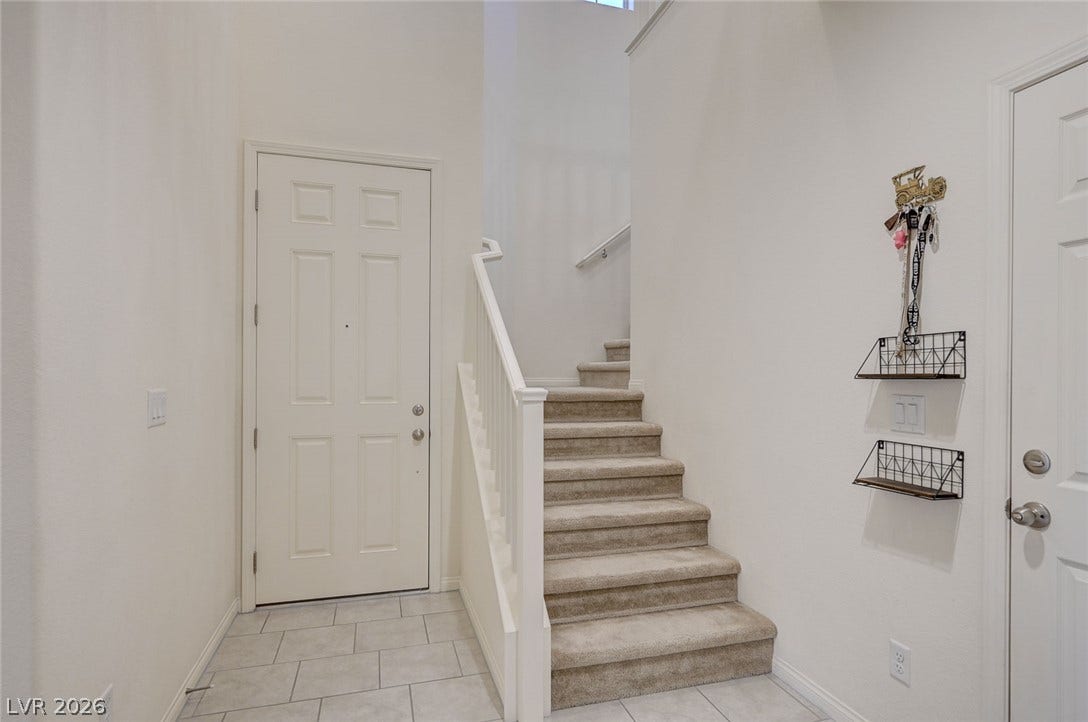 4114 Billowing Breeze Avenue, North Las Vegas, NV 89081 High ceilings and a carpeted staircase accent this light-filled entry hallway.