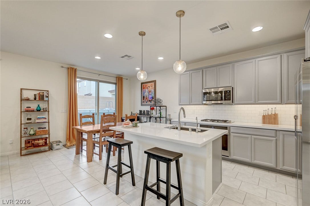 4114 Billowing Breeze Avenue, North Las Vegas, NV 89081 Gleaming stone countertops and modern cabinetry line this open, tiled culinary space.