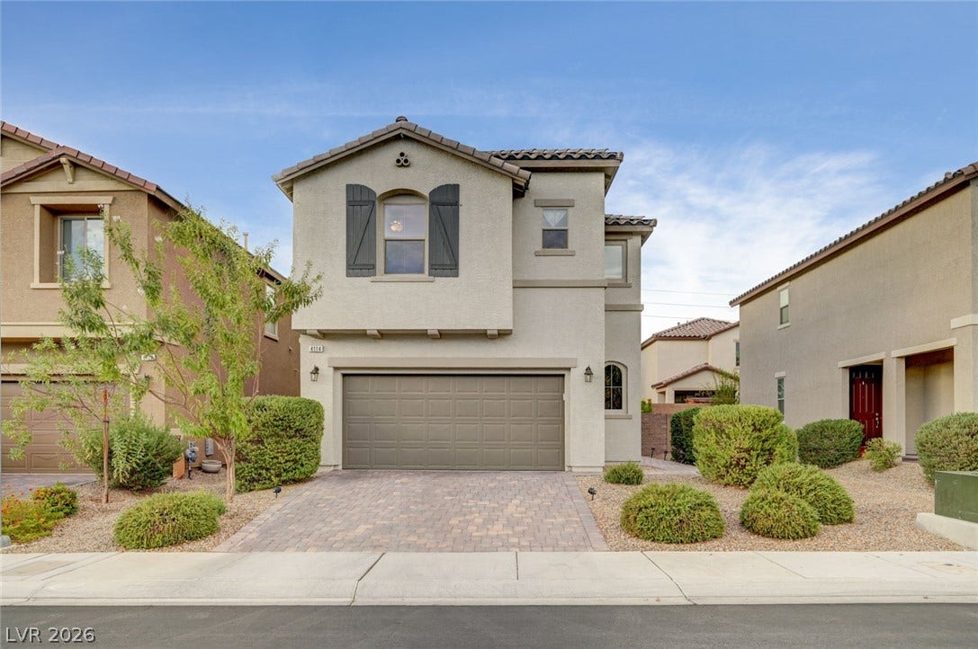 4114 Billowing Breeze Avenue, North Las Vegas, NV 89081 A paved driveway leads to the garage of this multi-level home featuring exterior shutters.