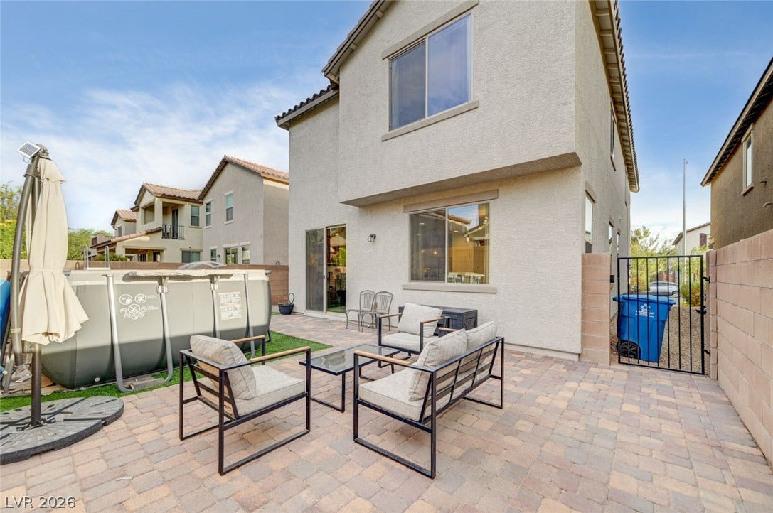4114 Billowing Breeze Avenue, North Las Vegas, NV 89081 A spacious stone paver patio offers an inviting outdoor retreat behind the stucco home.