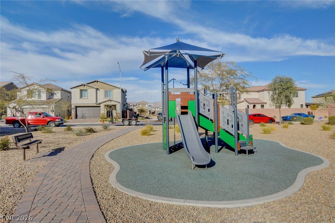 4114 Billowing Breeze Avenue, North Las Vegas, NV 89081 A paved path leads to a modern playground area set within a neighborhood community park.