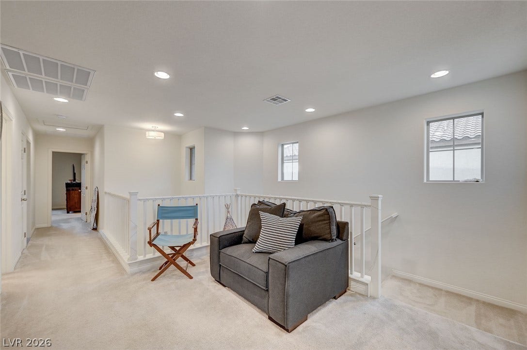 4114 Billowing Breeze Avenue, North Las Vegas, NV 89081 A versatile upper-level landing offers plush carpeting, recessed lighting, and a classic white banister.
