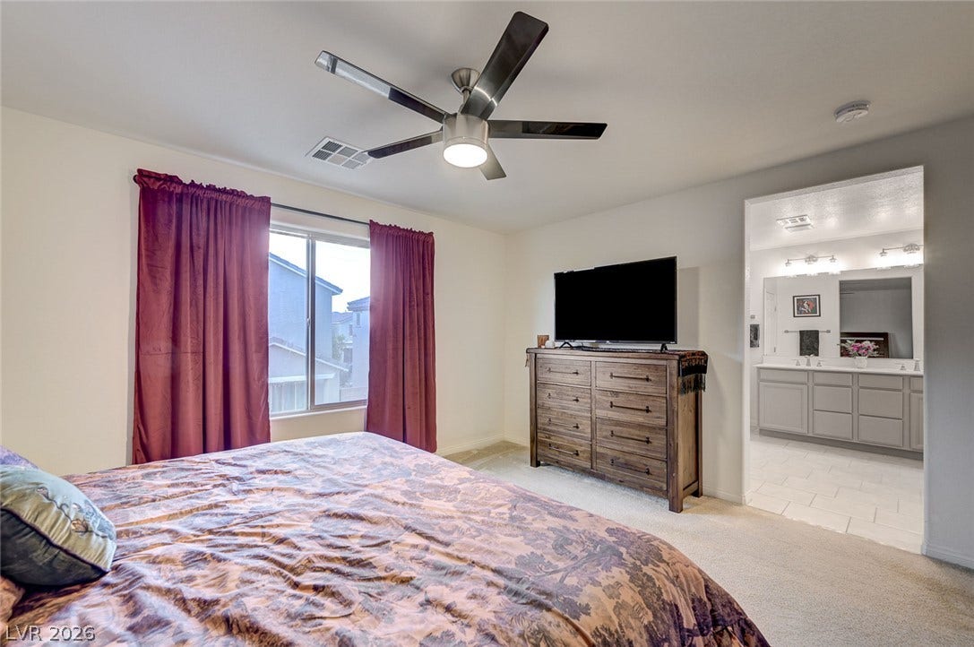 4114 Billowing Breeze Avenue, North Las Vegas, NV 89081 Plush carpeting and an adjacent en suite bathroom define this comfortable primary bedroom suite.