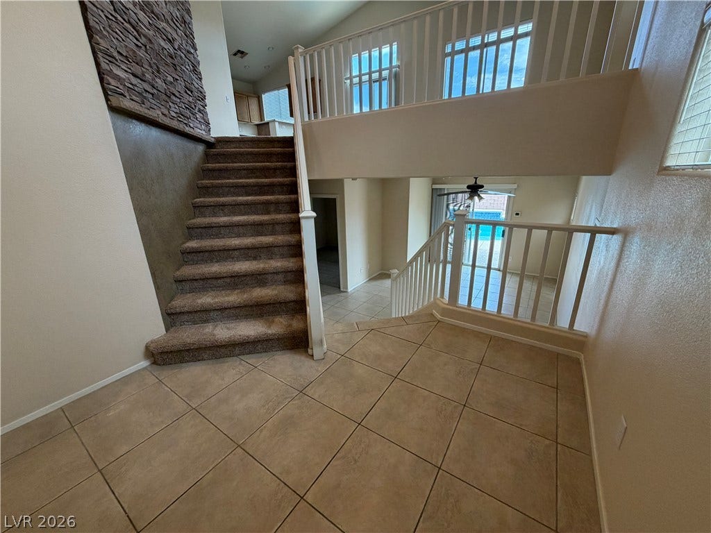 6420 W Casamar Street, North Las Vegas, NV 89086 A spacious entryway features tile flooring, carpeted stairs, and a stone accent wall.