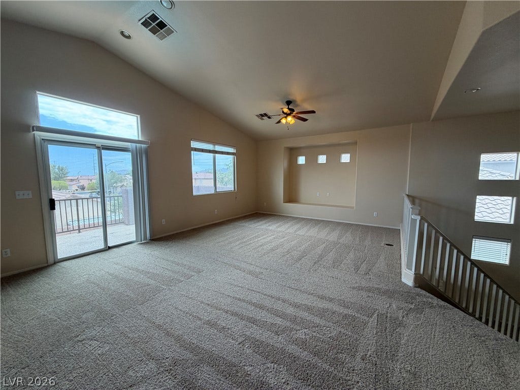 6420 W Casamar Street, North Las Vegas, NV 89086 Vaulted ceilings and broad sliding doors elevate this airy upper-level living space.