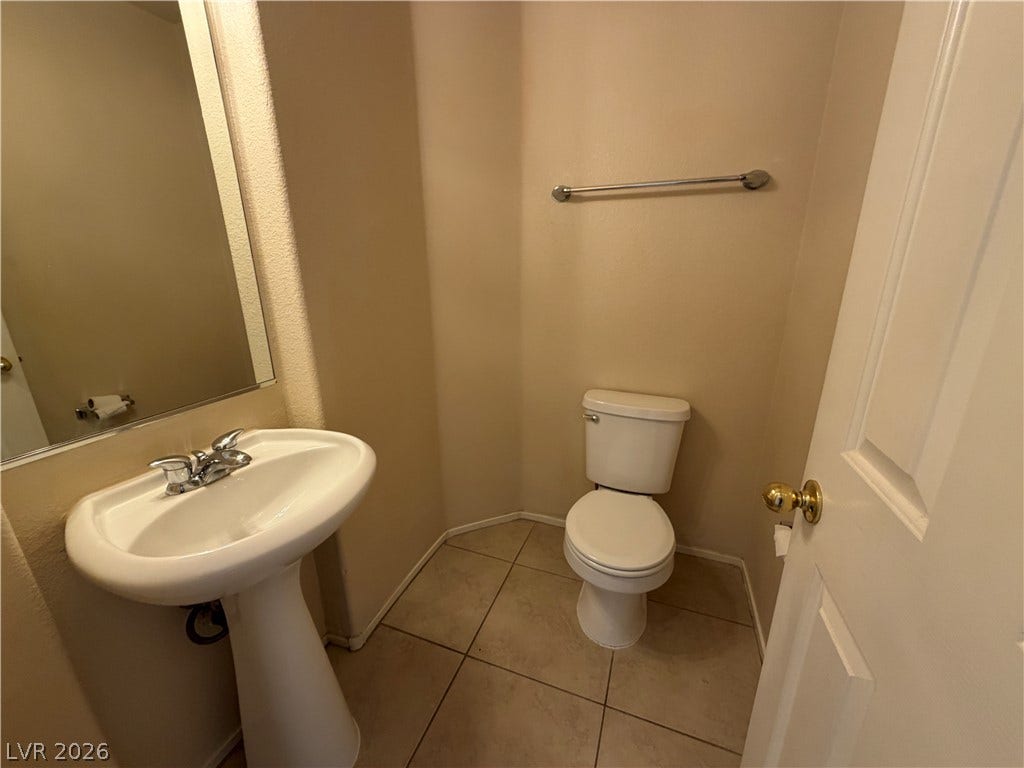 6420 W Casamar Street, North Las Vegas, NV 89086 Tiled flooring and a classic pedestal sink define this functional half bathroom.