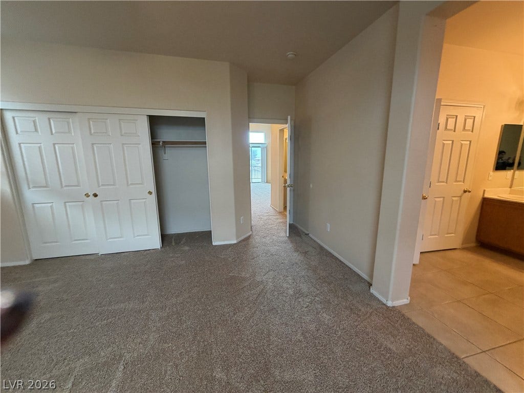 6420 W Casamar Street, North Las Vegas, NV 89086 A spacious bedroom features neutral walls, wall-to-wall carpeting, and an adjoining bathroom setup.
