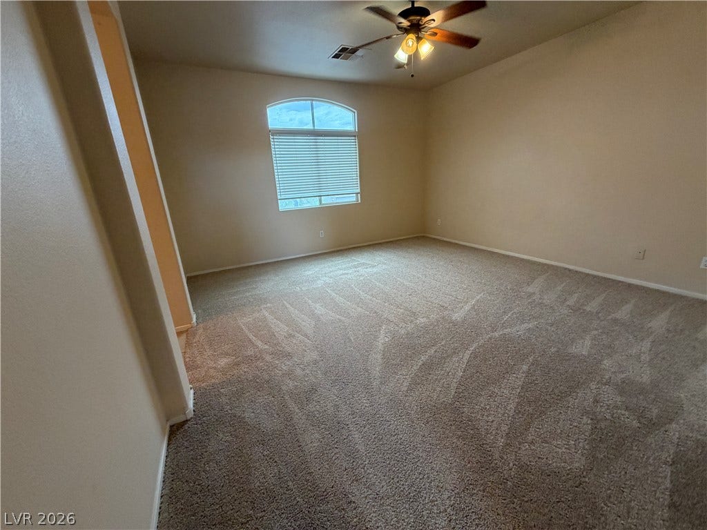 6420 W Casamar Street, North Las Vegas, NV 89086 A spacious arched window and plush carpeting define this serene bedroom space.