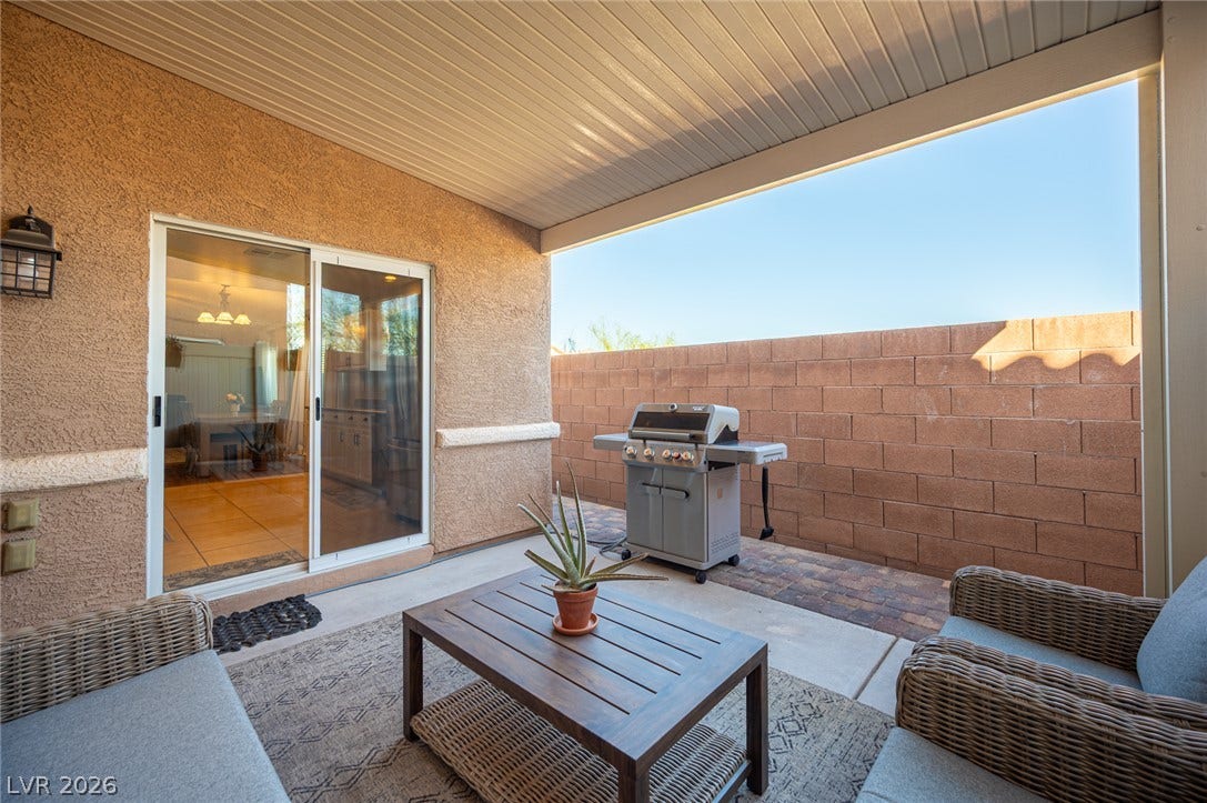 A covered patio with a textured ceiling opens to a private yard with block fencing.