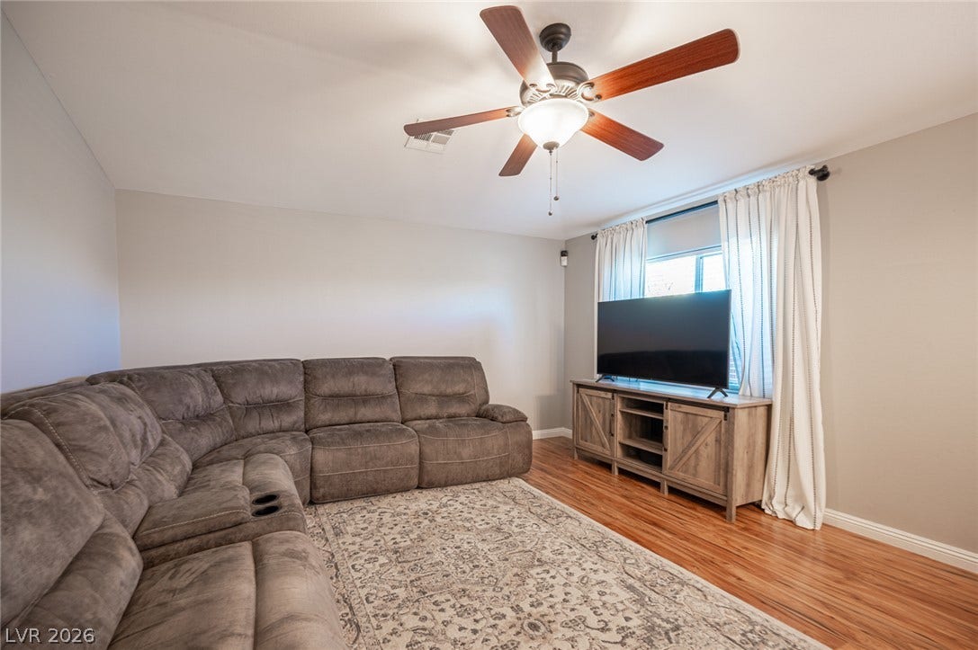 Rich wood flooring runs throughout this inviting living space illuminated by natural light.