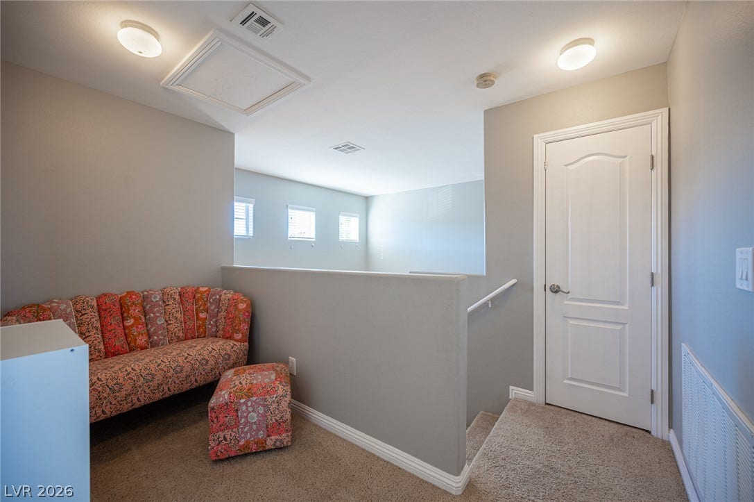 A spacious upper landing area connects levels with wall-to-wall carpeting and neutral finishes.