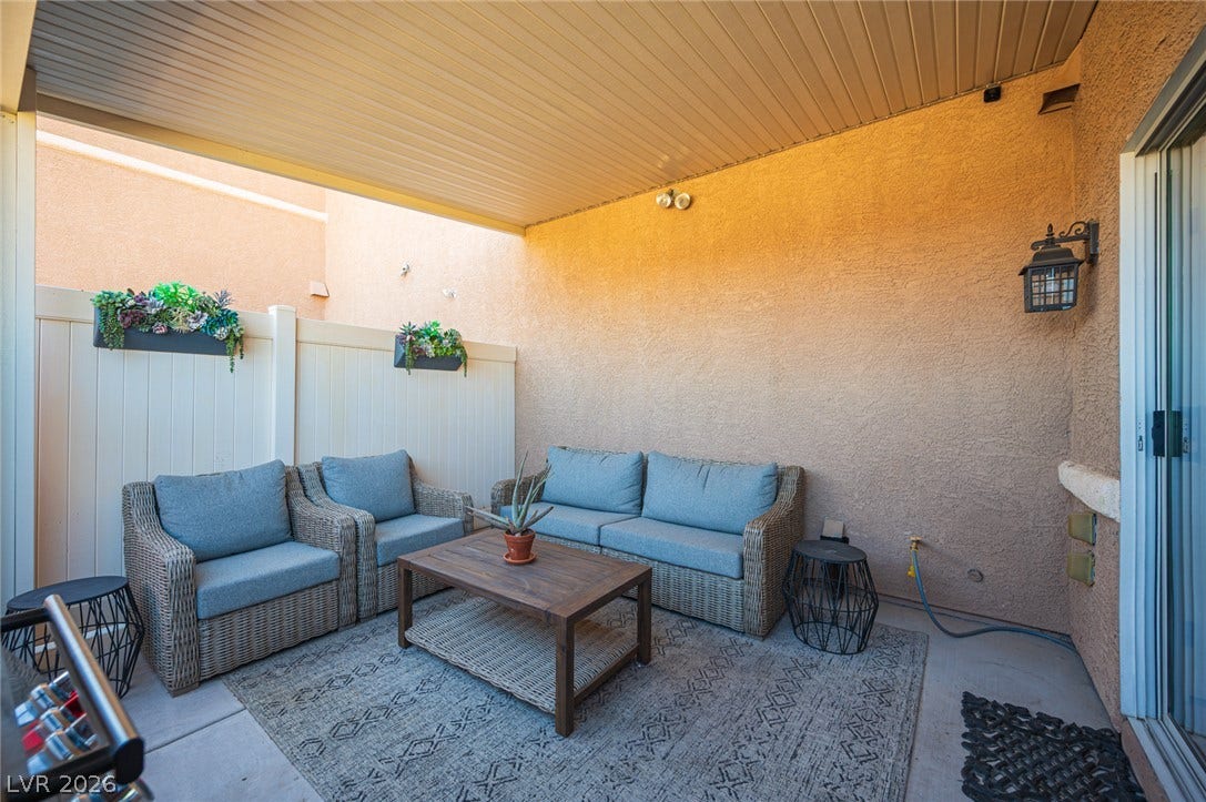 A covered concrete patio provides a private outdoor retreat framed by high stucco walls.