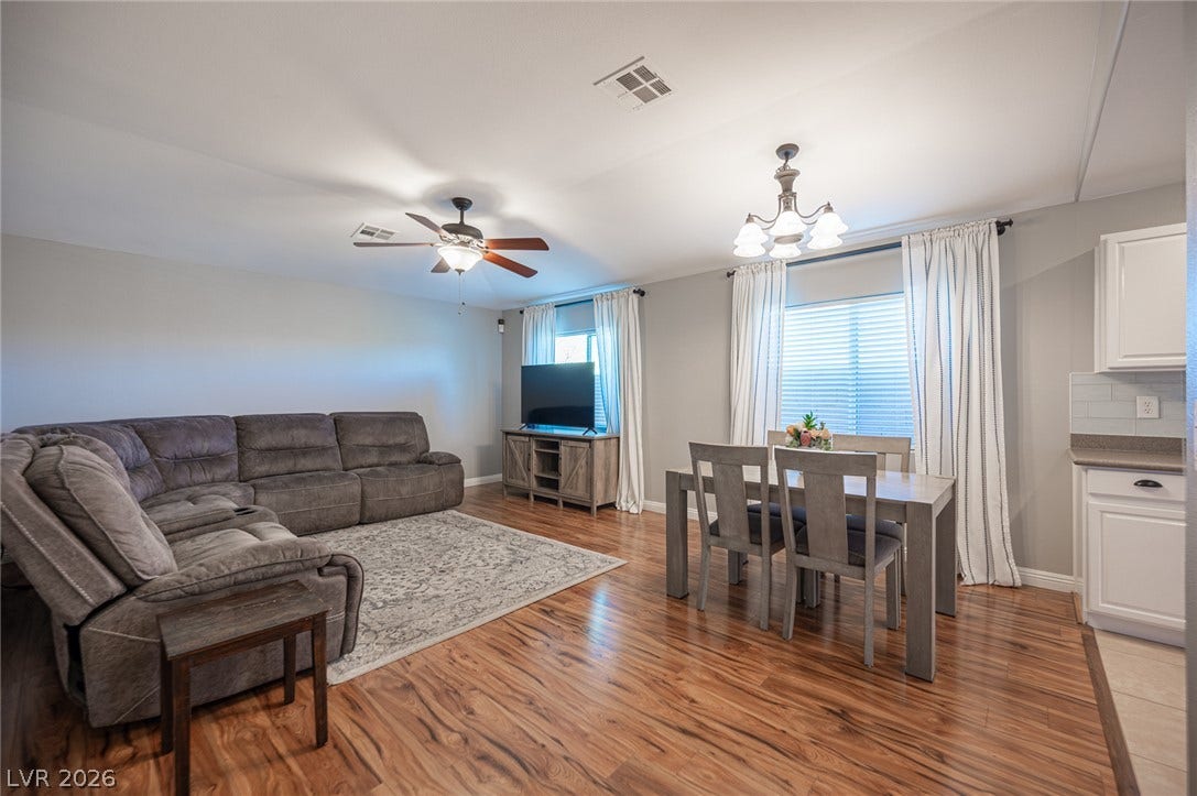 Rich wood flooring flows through this open layout connecting the dining and living spaces.