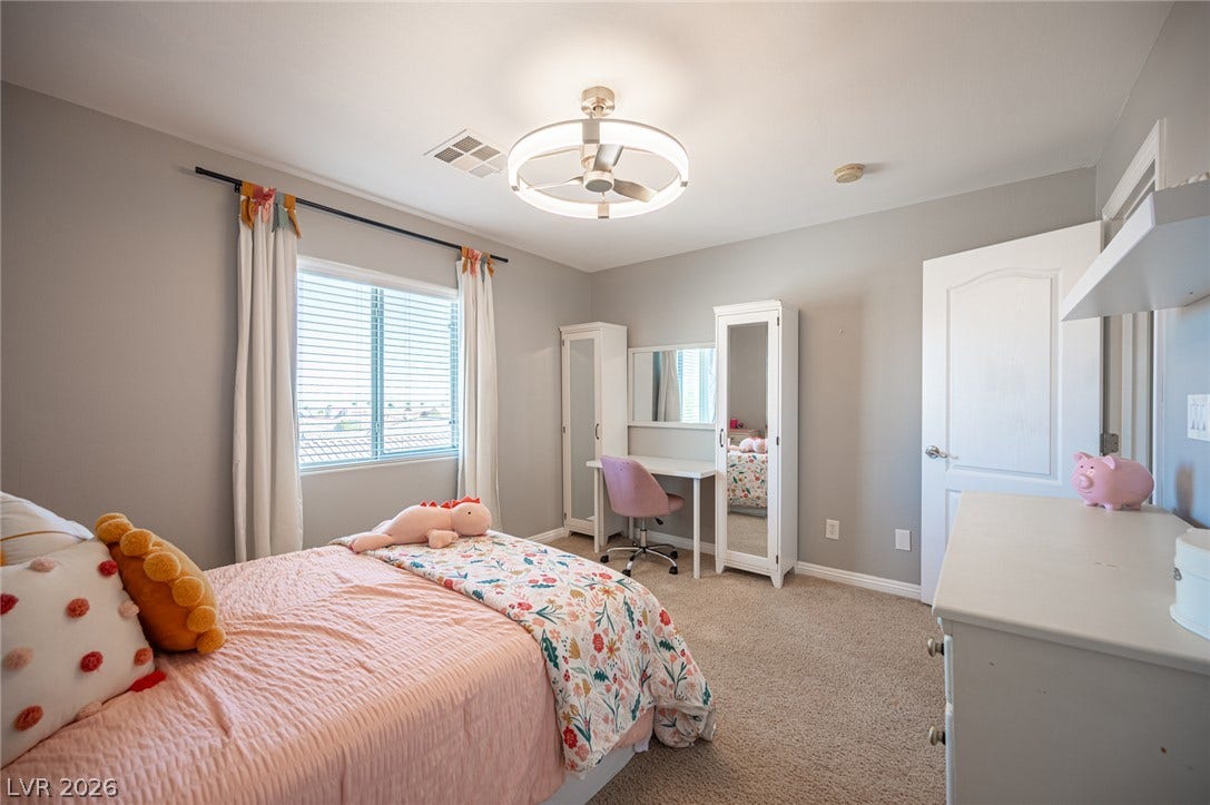 A spacious bedroom with plush carpeting and a large window offering ample natural light.