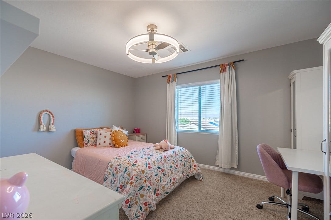 Plush carpeting and a large window defining this comfortable bedroom space.