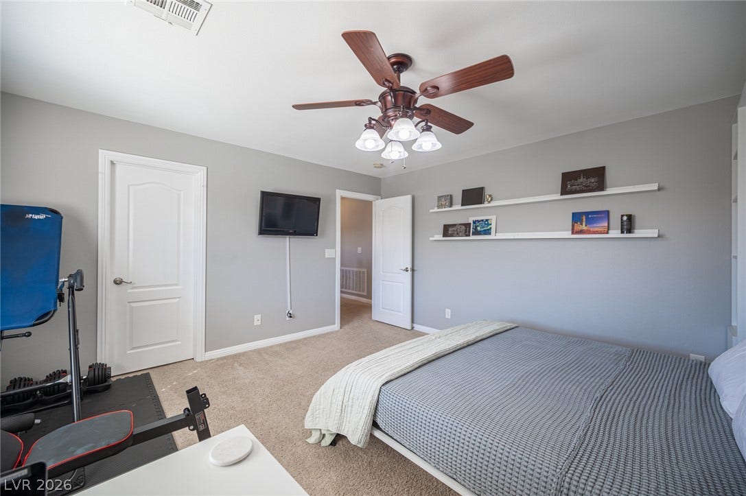 Smooth carpeting and floating display shelves highlight this comfortable bedroom.
