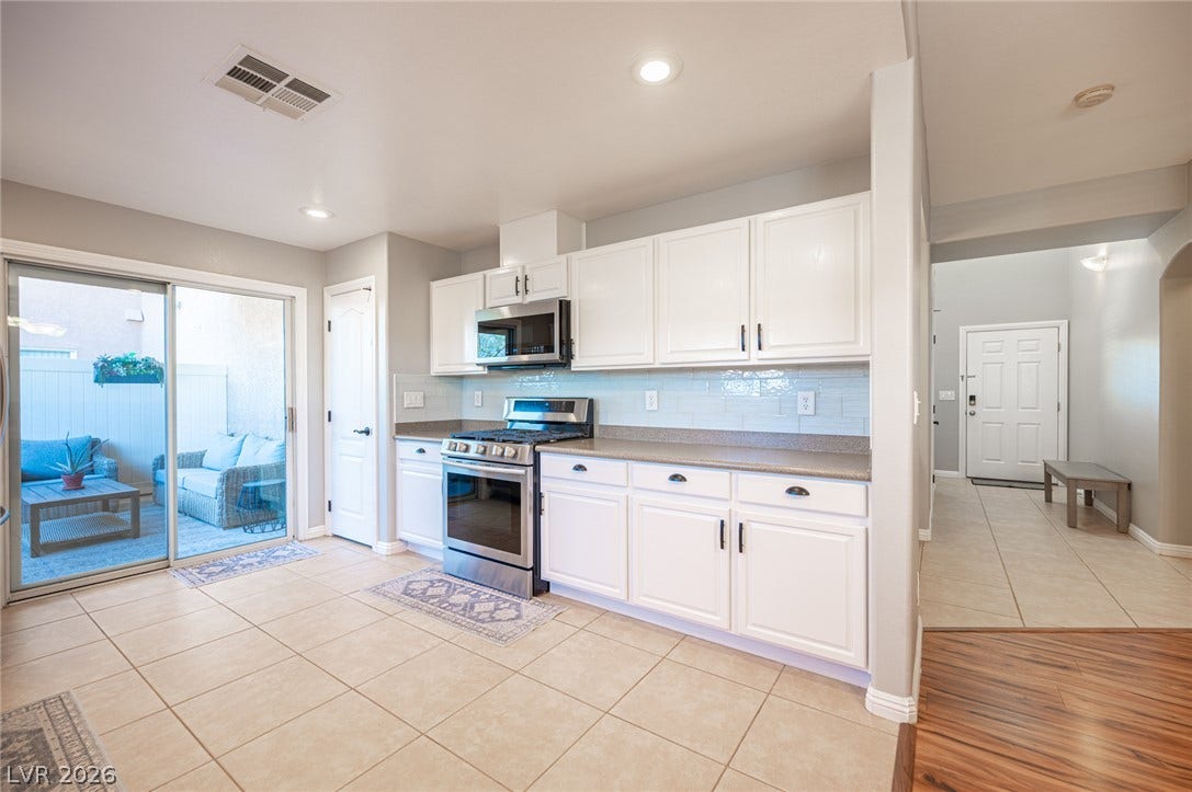 Tiled flooring and white cabinetry define this kitchen space opening directly to the outdoors.
