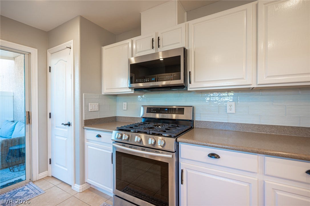 White cabinetry stands out against tile backsplashes and durable stone-look countertops in this kitchen.