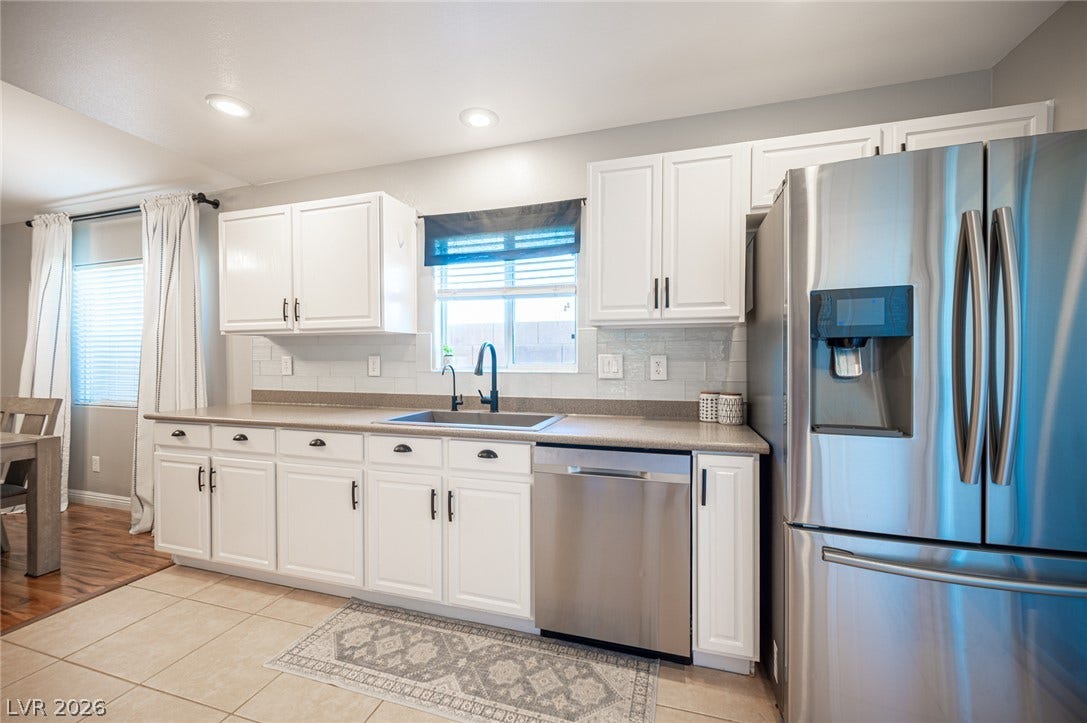 Gleaming stainless steel appliances complement the bright cabinetry and crisp tile flooring.