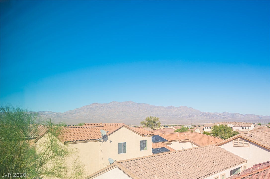 Distant mountains frame the surrounding neighborhood skyline under a clear blue sky.