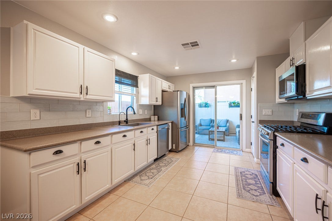 A sliding glass door opens from the tiled kitchen to a private backyard patio.