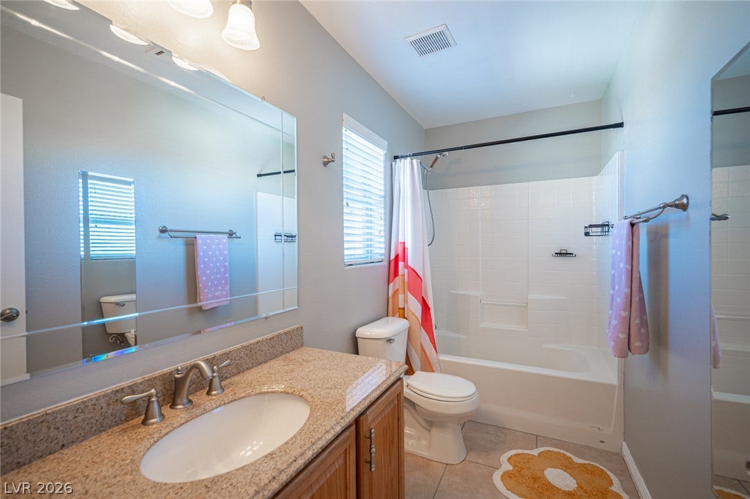 A classic bath presents a granite-topped vanity paired with a traditional tub and shower combination.
