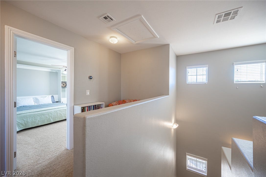 An upper-level landing features plush carpeting and looks down over the staircase.