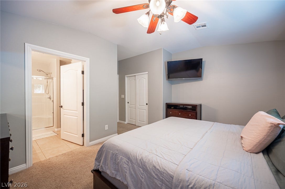 A spacious bedroom features direct access to an en suite bathroom and plush carpeted flooring.