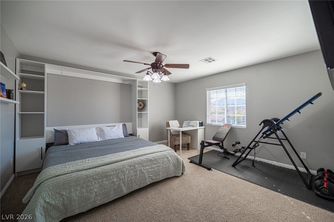 Generous natural light fills this versatile space featuring wall-integrated shelving and soft carpet flooring.
