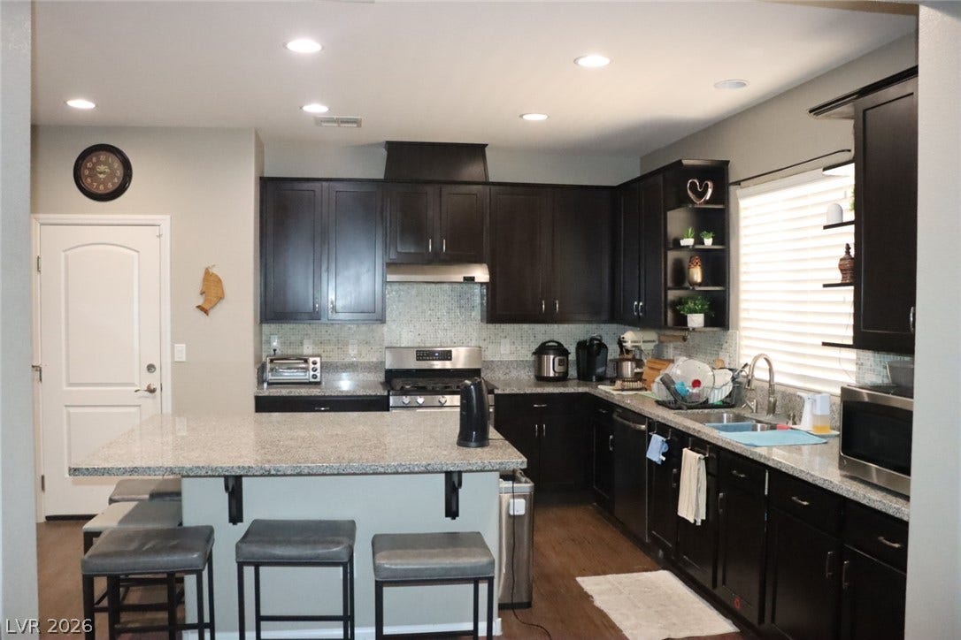 Rich dark cabinetry pairs with granite countertops and a central island in this kitchen.