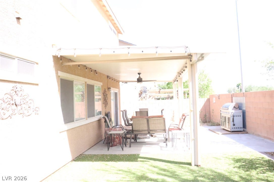 A shaded patio covers a concrete lounging area alongside a grassy backyard retreat.