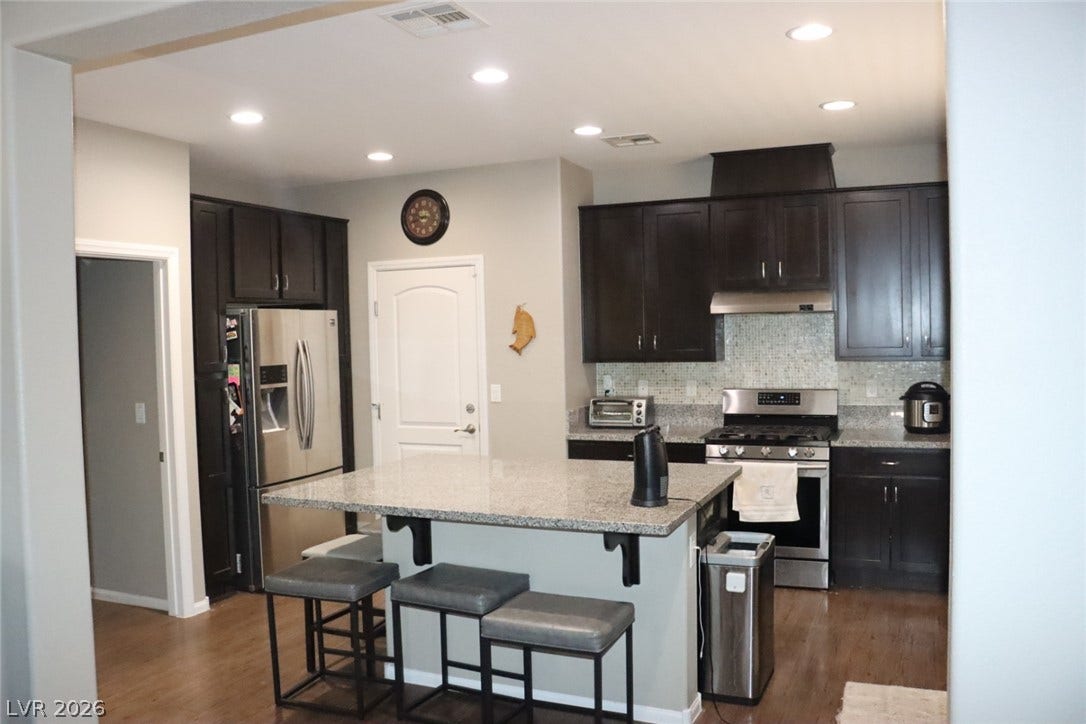 Dark cabinetry and granite countertops frame the functional island in this open-concept kitchen.