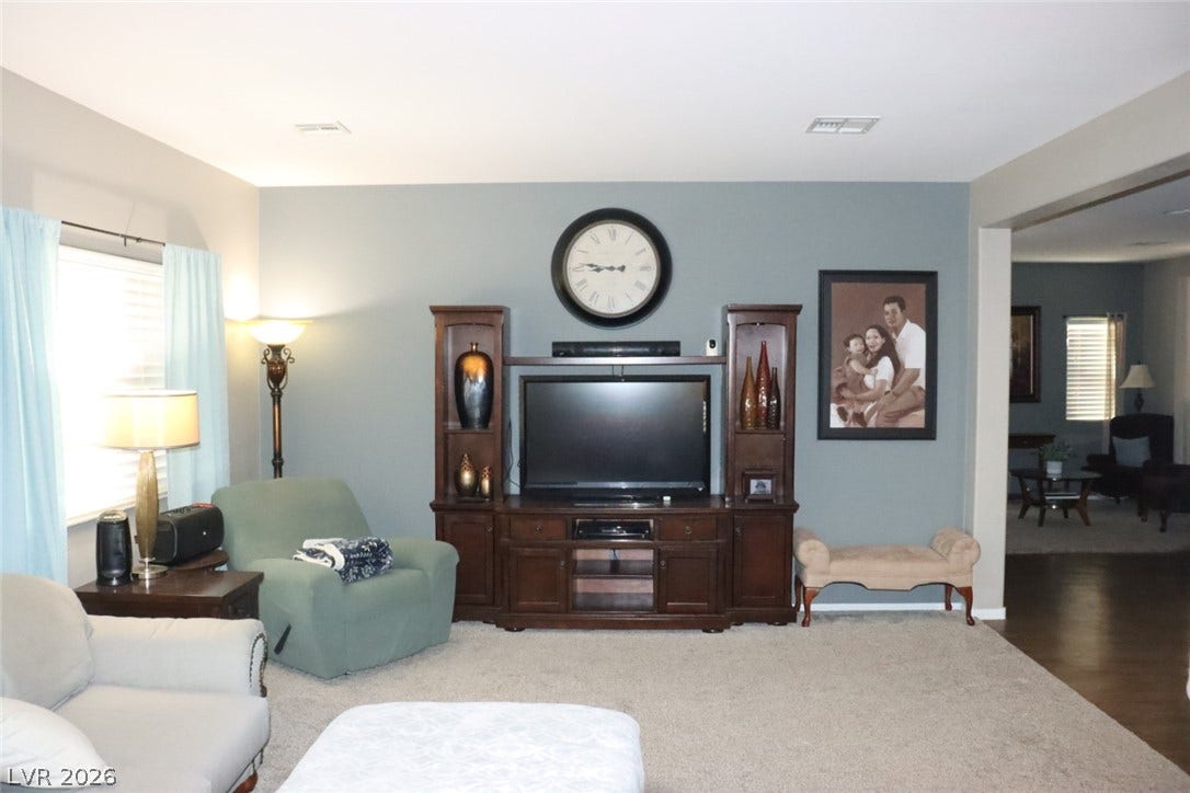 Plush carpeting and an open archway define this comfortable living area.