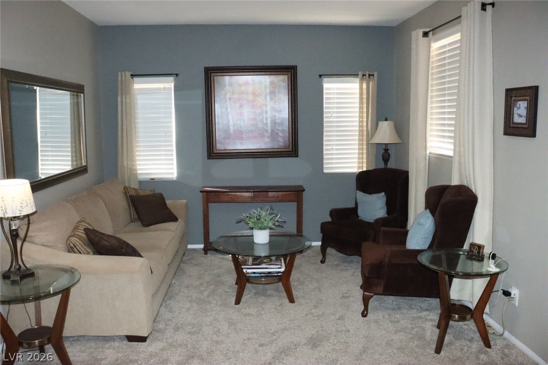 Plush wall-to-wall carpeting and symmetrical windows define this comfortable living area.