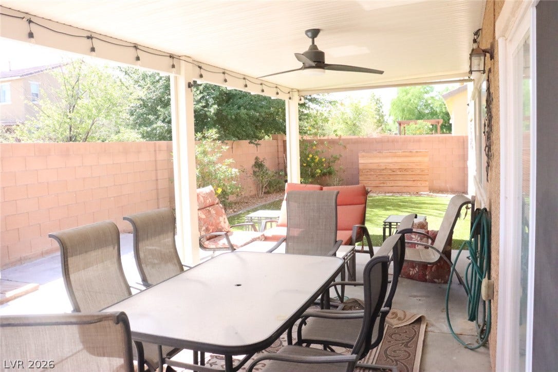 An inviting covered patio looks out onto a private yard enclosed by masonry fencing.