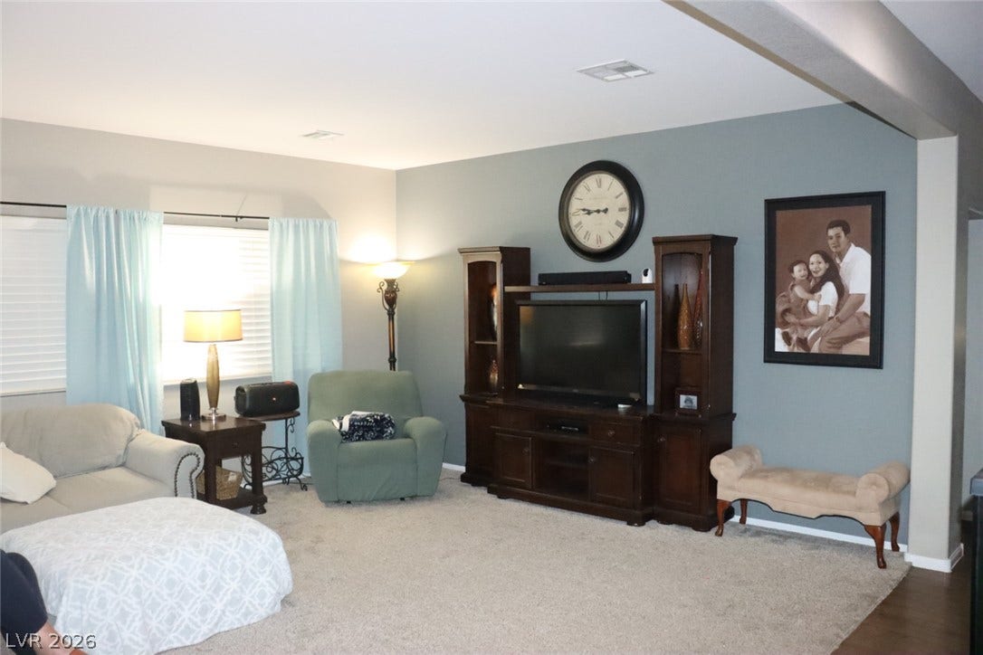 Plush carpeting anchors this inviting living space illuminated by large windows.