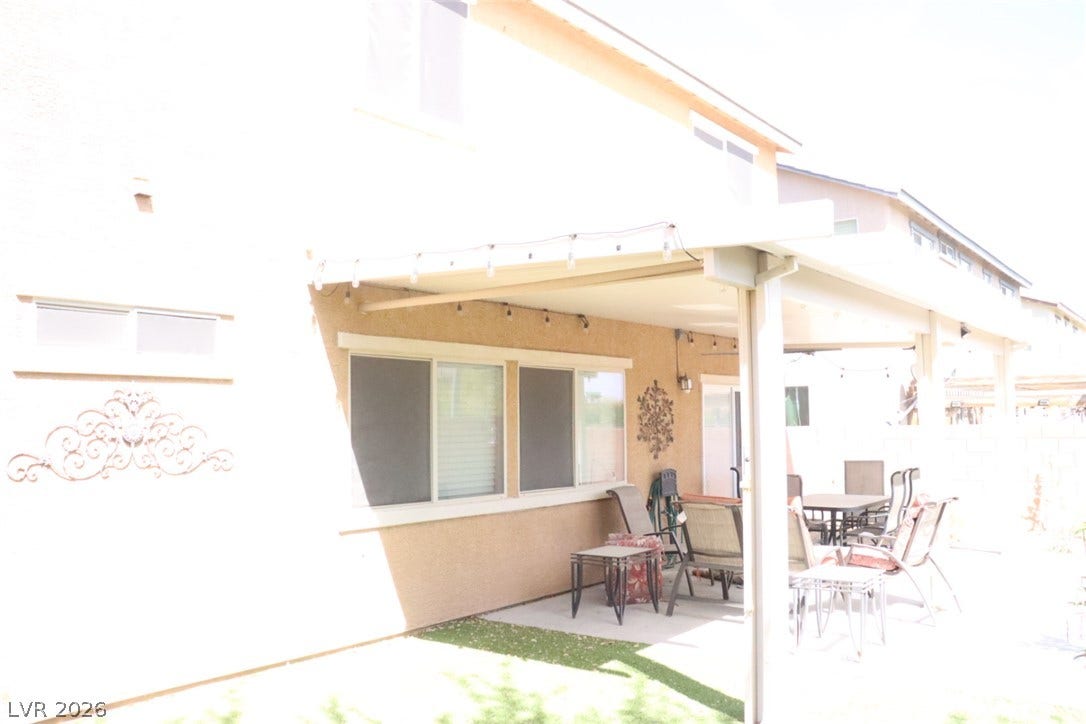 A spacious covered patio sits alongside the stucco exterior, opening to the backyard.